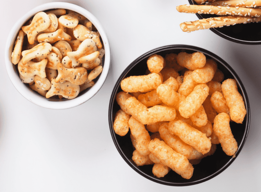 Main image for the article [Salt for babies: How much is too much?. Pictured is a bowl of goldfish crackers, pretzel sticks and a bowl of cheese puffs.