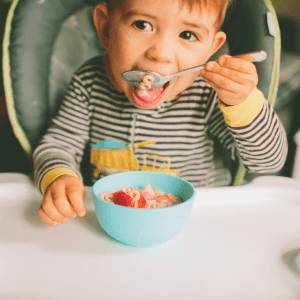 2 year old toddler drinking whole milk in a cup, and eating peanut butter cookie