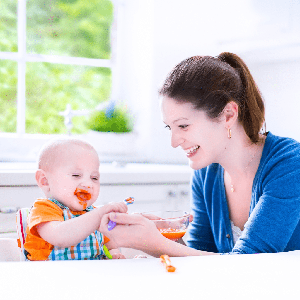 When is the right time to start solids? Mother spoon feeding her infant baby food