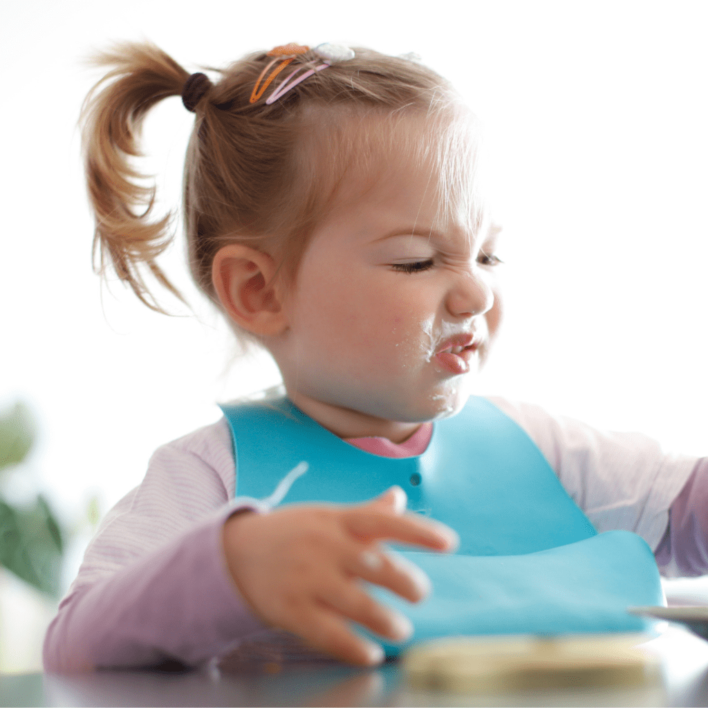 Main image for the article [Avoiding Food Ruts With The “Rotation Rule” ﻿]. Pictured is a toddler sitting at the table and making a disgusted face at her food.