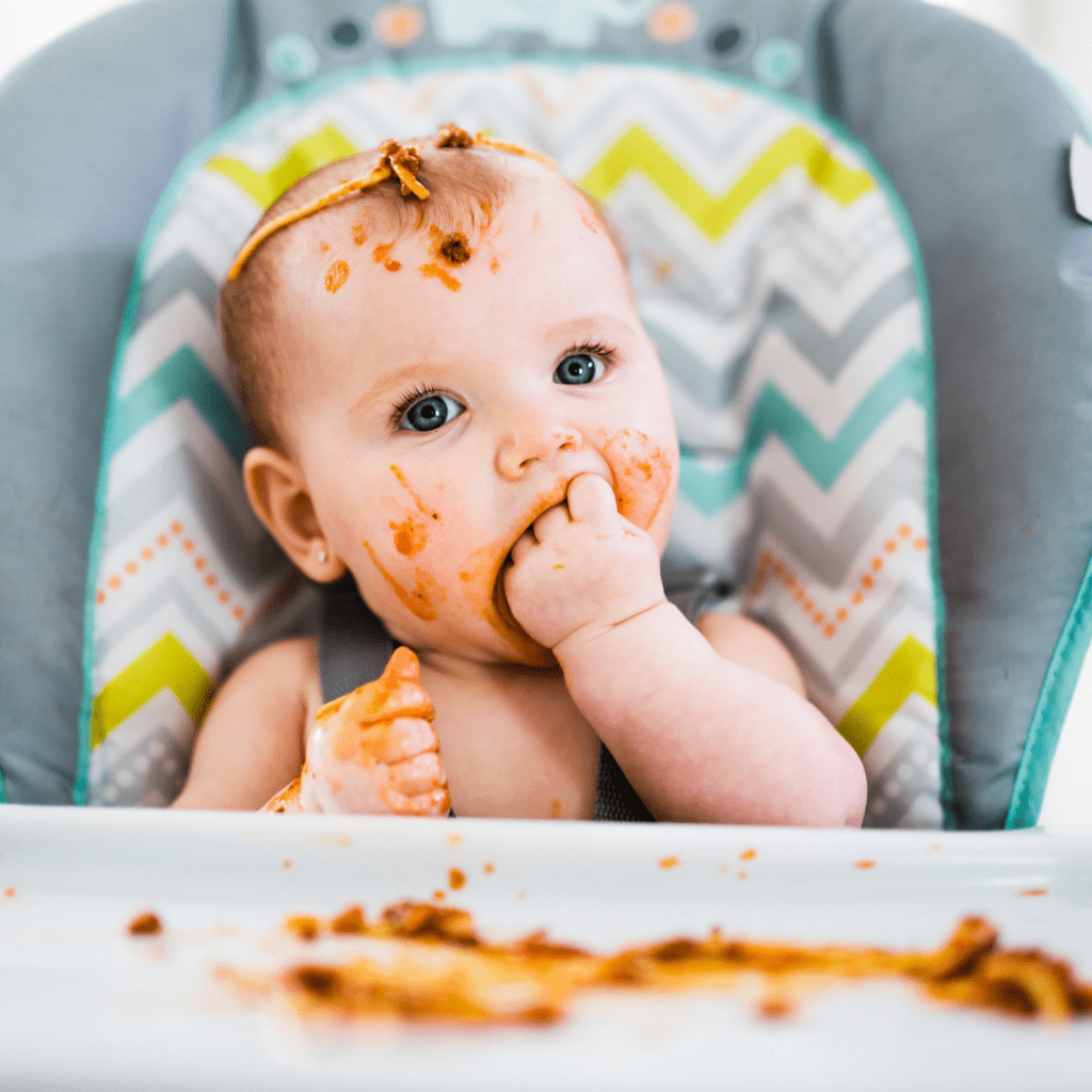 Episode art for episode "#5: How Much Should My Baby Be Eating?". Pictured is a baby sitting in a highchair eating spaghetti.