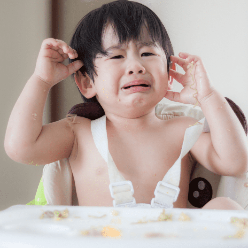 Episode art for episode "#9: The ONE Feeding Strategy that will Change Mealtimes Forever. Pictured is a toddler sitting in a highchair crying.