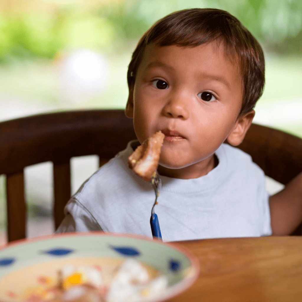 Episode art for episode: "#46: A deep dive into the best fish for your baby (and what to avoid)." Pictured is a baby sitting at the table eating a piece of fish fillet.