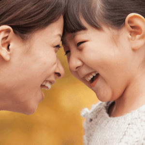 Featured image for the article "Parenting styles: What authoritative parenting is and why it’s recommended." Pictured is a mother and daughter smiling at each other, face-to-face.