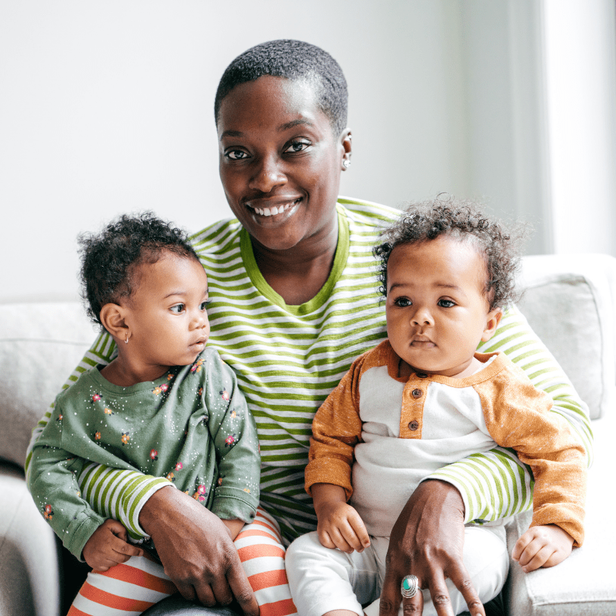 Featured image for the article: "Top tips for introducing solids to twins from Moms who’ve done it!". Pictured is a mom holding her twin babies.