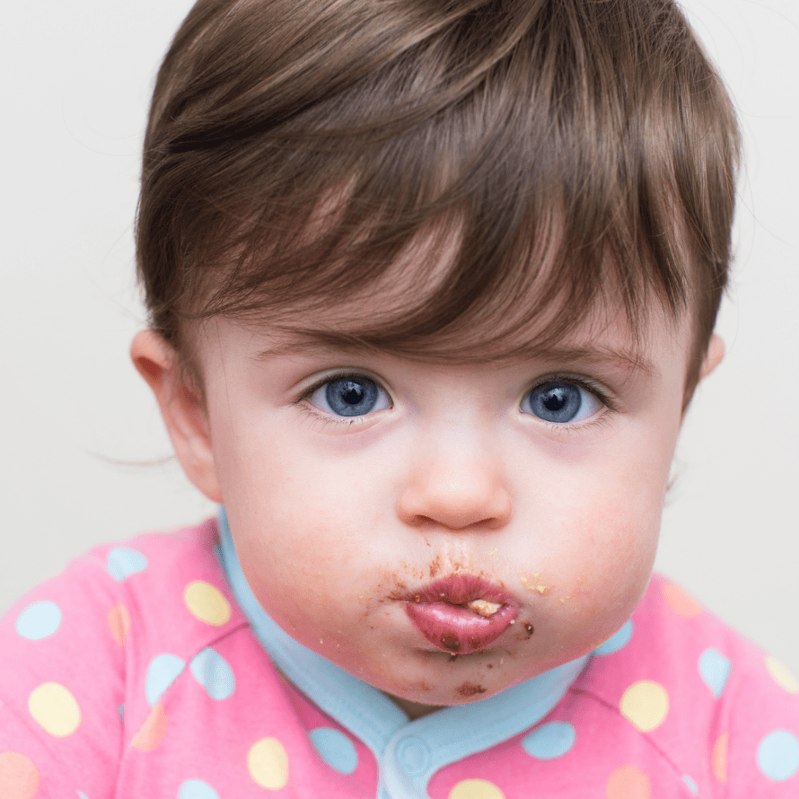 Baby with a full mouth of food after mouth stuffing.